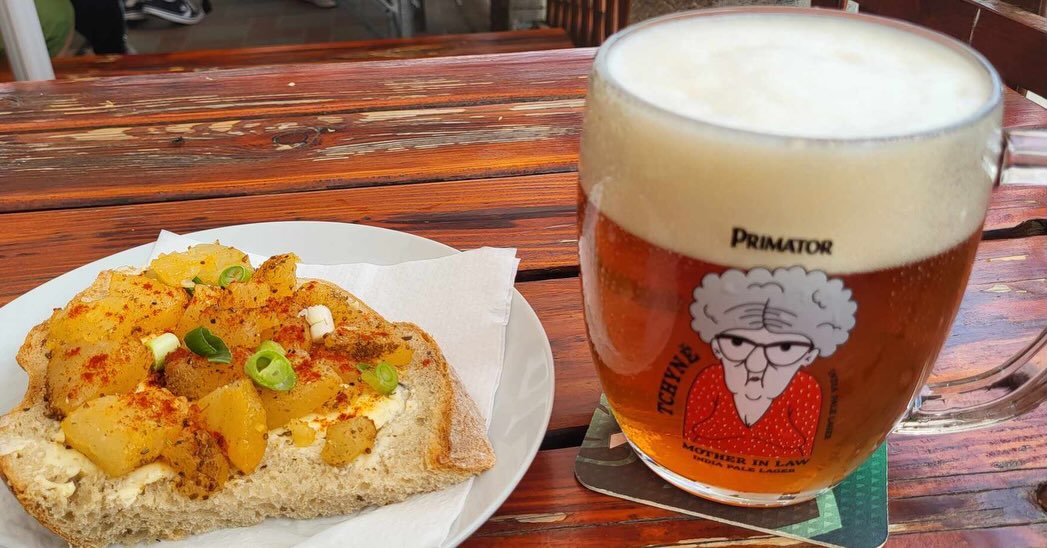 Talíř s jídlem a pivo Primátor na zahrádce